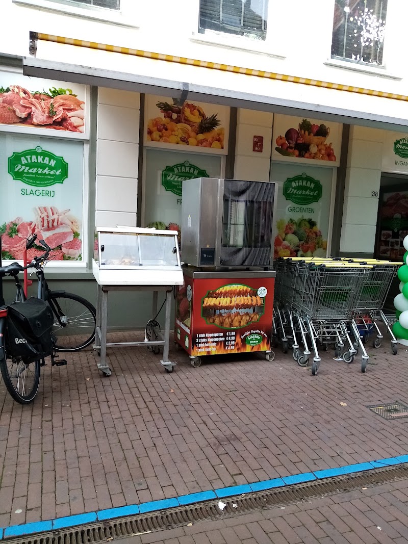 De pui van Atakan Market met de geel-witte luifel, de panelen slagerij, groenten en fruit, en de grill met kip op de stoep.