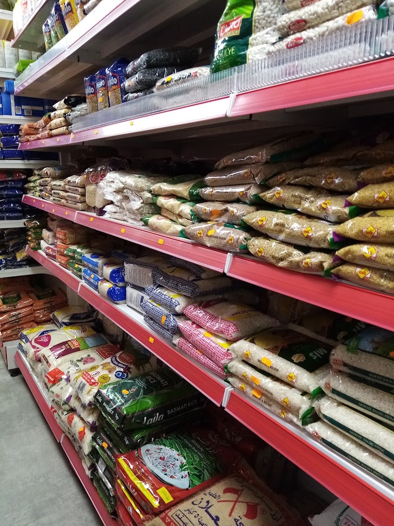 Schappen vol zakken rijst, bulgur, peulvruchten en pasta in verschillende soorten.