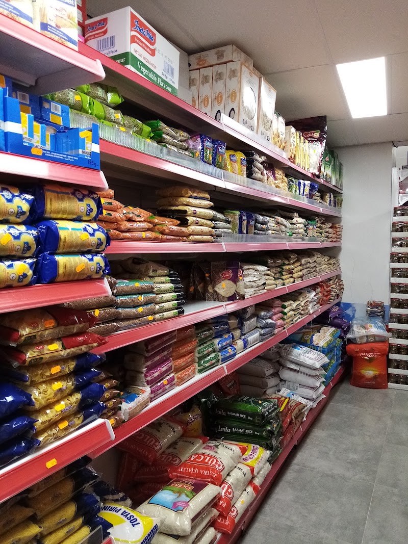 Een gang in de winkel met volle schappen van vloer tot boven, tot achterin de zaak.